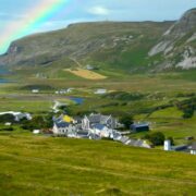 Beautiful village beside the sea with a rainbow dipping into ocean.