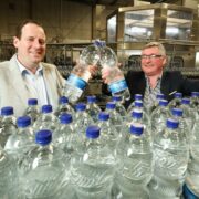 Two men behind bottles of water.