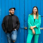 Man and woman in front of blue gate.