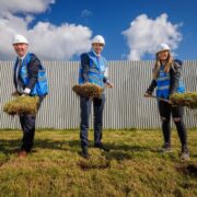 Three people lifting sods of earth.