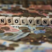 Insolvency written in scrabble on top of Euro cash.