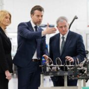 Woman and two men inspect aircraft parts.