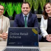 Two women and a man behind a notebook computer.