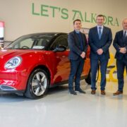 Four men beside ORA electric car.