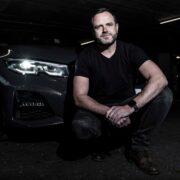 Man on knee in front of a car.