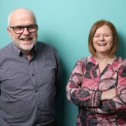 Man and woman in front of a green background.