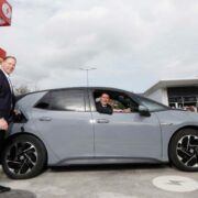 Two men with an electric car being charged.