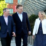 Two men and a woman walking down a street.