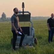 Two men in a field with an animal weighing machine.