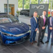 Four men beside a new blue car.