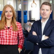 Woman in red jacket and man in dark suit.