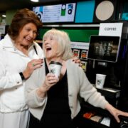 Women laughing at a coffee machine.