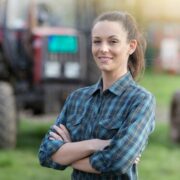 Woman farmer standing in front of tractors.