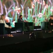 Three people on stage at a conference.