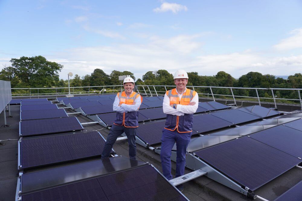 Two men on a rooftop with solar panels.
