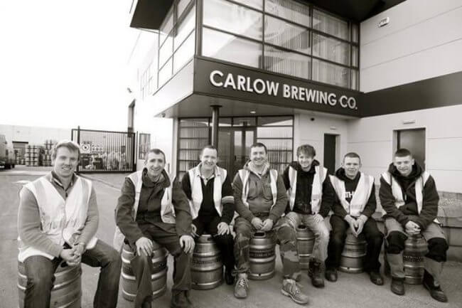 group of men sitting on beer kegs.