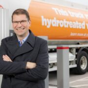 Man with arms folded in front of a truck with HVO renewable diesel.