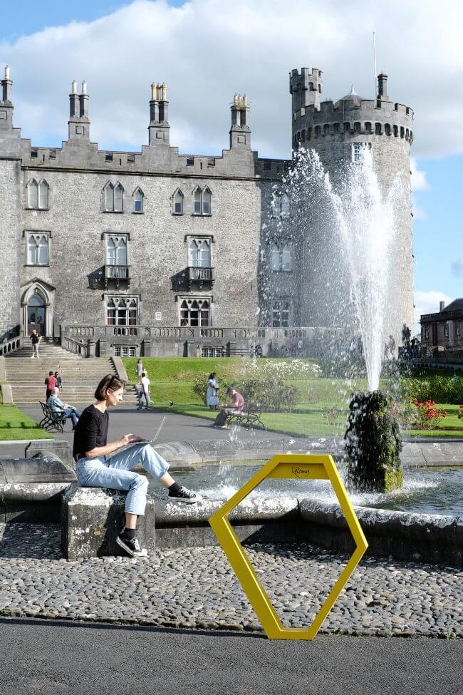 Woman remote working in front of Kilkenny Castle.