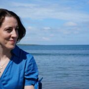 Woman in blue beside the sea.