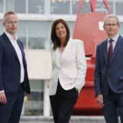 Two men in suits and a woman in a white jacket.