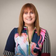 Red-haired woman in patterned dress.