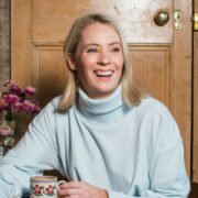 Woman holding a cup of tea laughing.