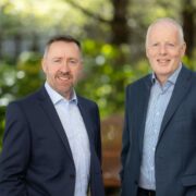 Two men in suits in the woods.