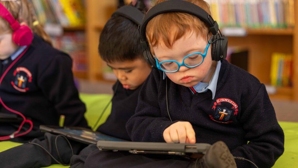 Boy wearing blue glasses using an iPad to read.