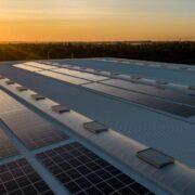 Sun shines on solar panels on roof of a building.