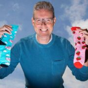 Man in blue sweater holding colourful socks.