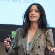 Woman in grey jacket making a presentation.