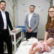 Two men and a woman demonstrating medtech for newborn babies.