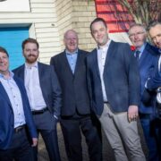Six men outside a building beside a smart locker system.