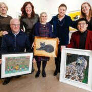 Group of people holding paintings.