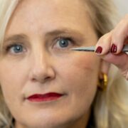 Woman holding tiny medical stent device between a tweezers.