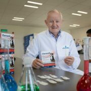 Man in pharma lab wearing white lab coat.