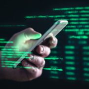 Smartphone with green software code in background.