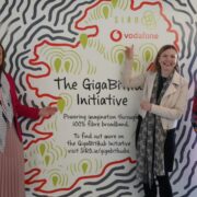 Three women in front of a colourful banner.