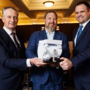 Three men hold a space tech device.