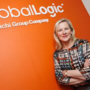 Woman leaning against orange wall.