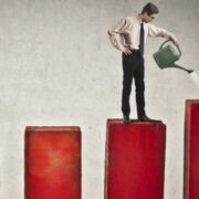 Businessman watering bar charts, denoting having time to think about ways to grow the business.