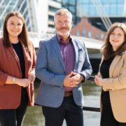 Two women and a man in front of the Liffey in Dublin.