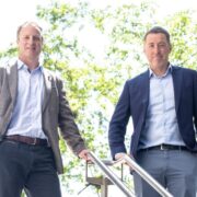 Two men in blazers on a staircase.
