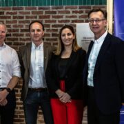 Three men and a woman in front of a brick wall.