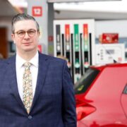 Man standing in petrol station forecourt.