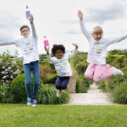 Three kids in white t-shirts jump into the air.