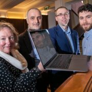 Three men and a woman with a laptop.