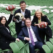 Two men and two women holding an American football and helmet.