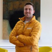Man in yellow jacket with arms folded.
