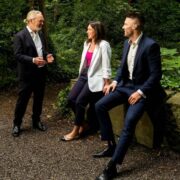 Two men and a woman chatting in a garden.